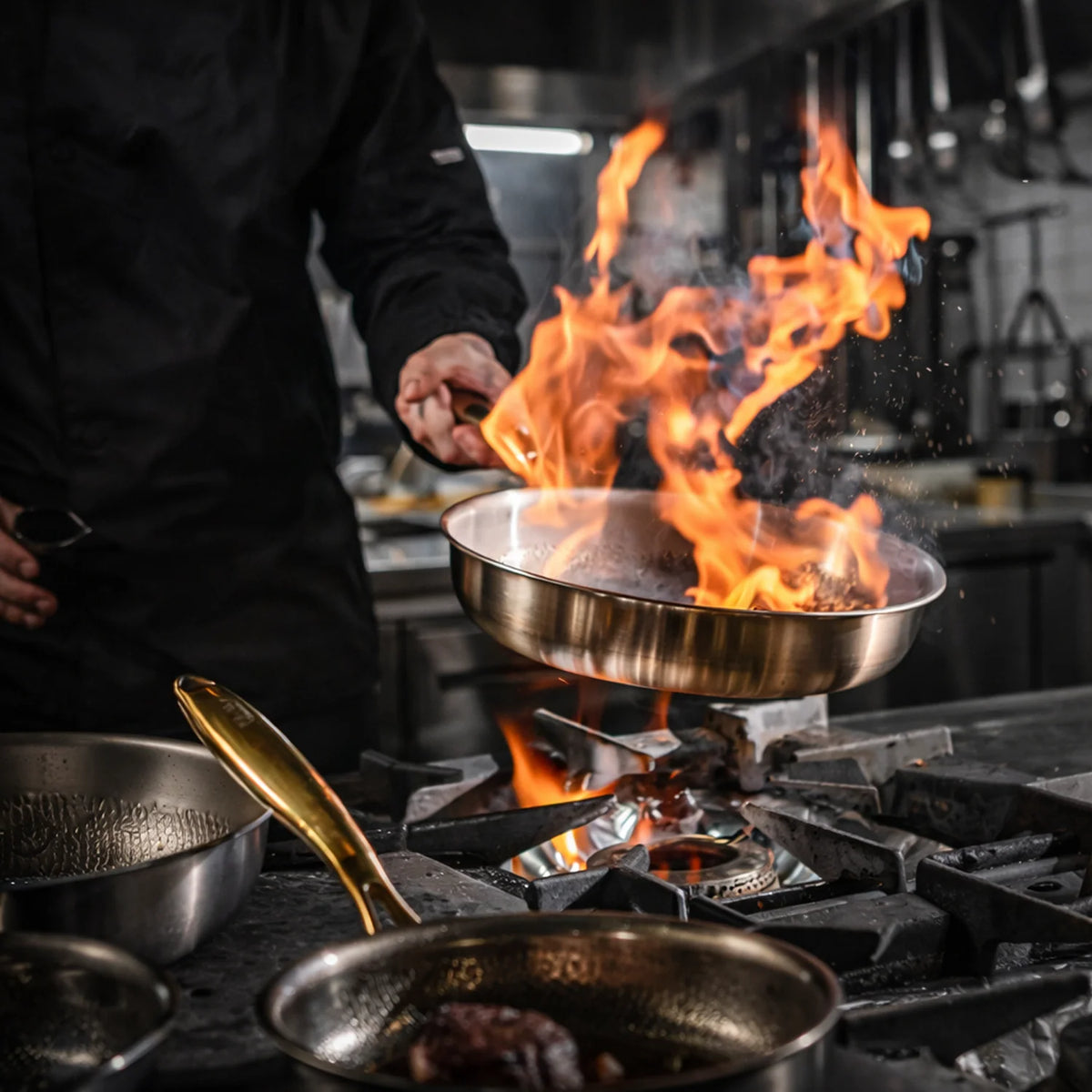 Chef réalisant un flambage dans une poêle en titane Maison Ferré® sur un feu vif