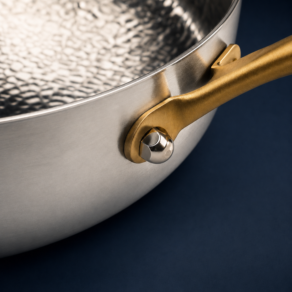 Détail du manche or et du rivet sur une poêle martelée en titane Maison Ferré®